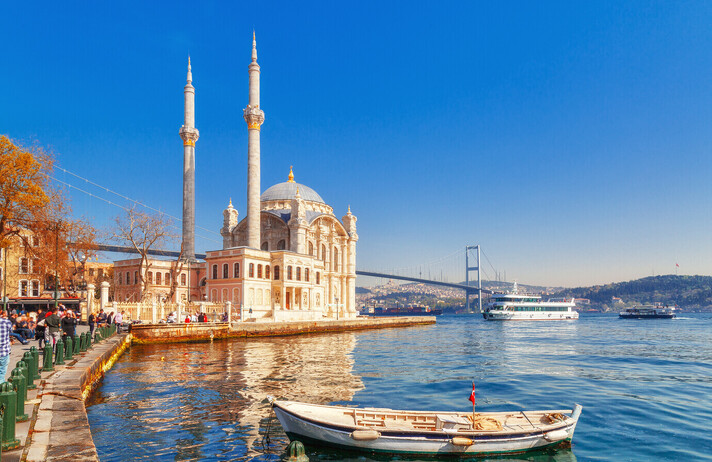 Ortakoy cami - famous and popular landmark in Istanbul, Turkey. Lovely spring scenery with fishing boat at foreground and old historical mosque Ortakoy and Istanbul Bosporus bridge at background.
